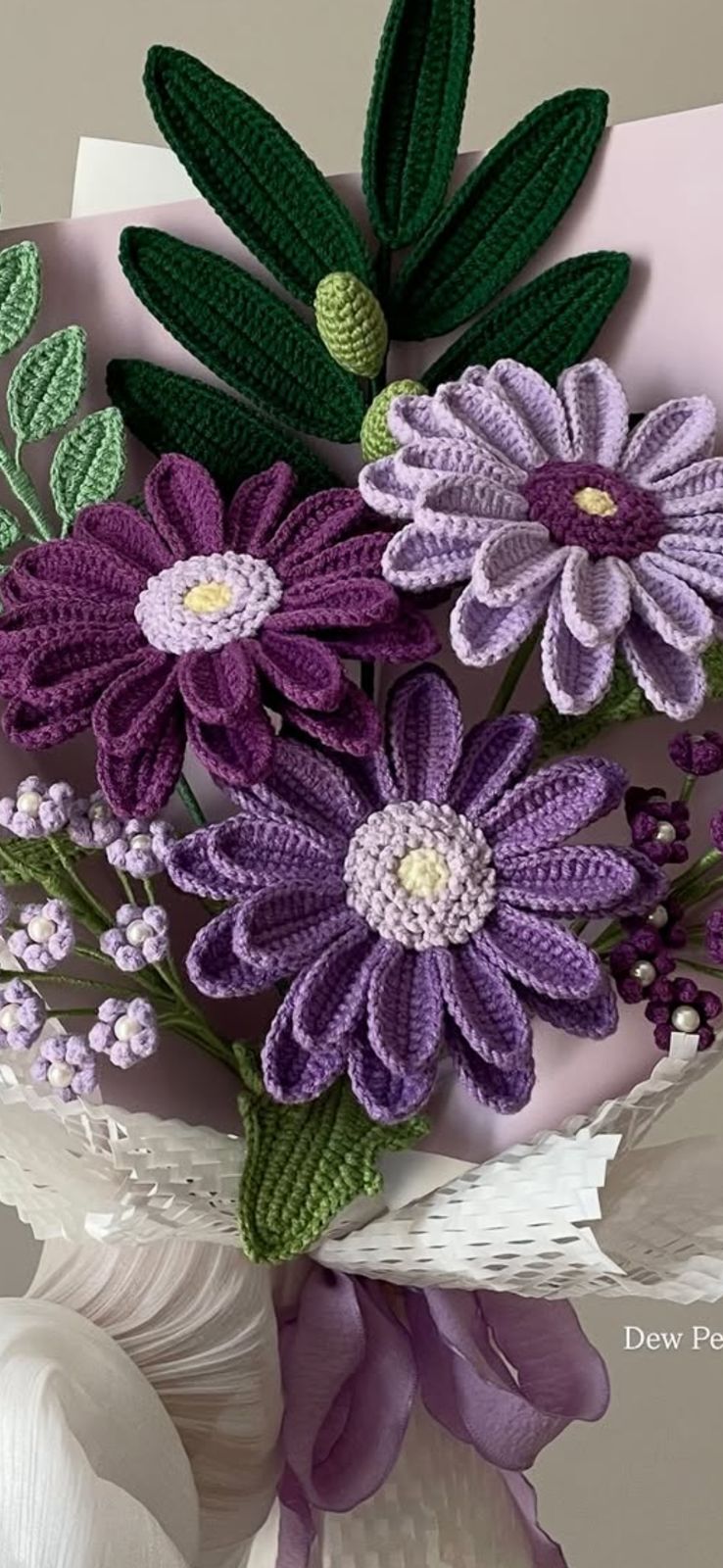 A hand-tied bundle of colorful crochet tulips in pink, yellow, and purple.