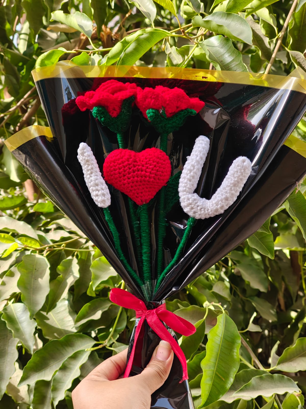 Single romantic red crochet rose with detailed layered petals on a green stem.