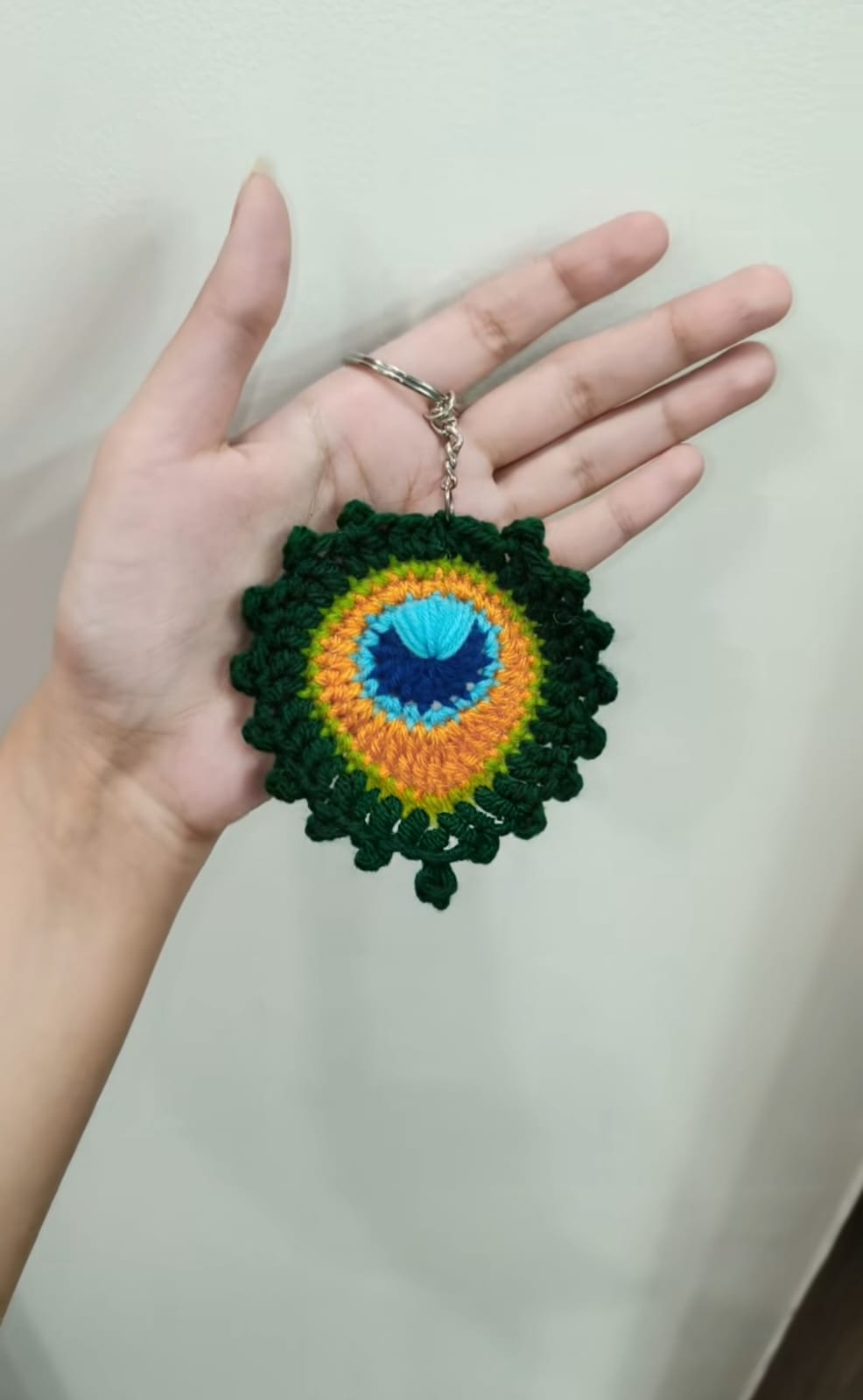 Mini amigurumi avocado keychain with a brown seed center and happy embroidered face.